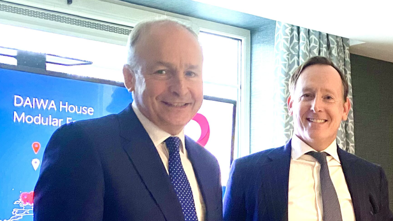 Micheál Martin und George Salden (CEO DAIWA HOUSE CB B.V. - DACH) bei einem Treffen in Cork vor einem Bildschirm mit der Aufschrift „DAIWA House Modular“